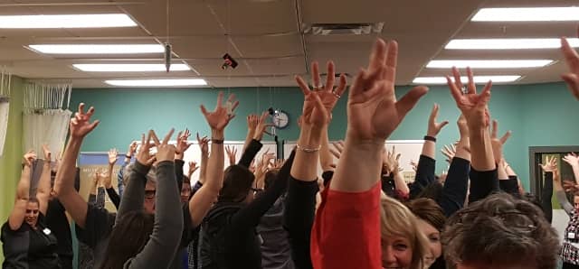 Everyone at the networking event participating in a group exercise, with all their hands up in the air